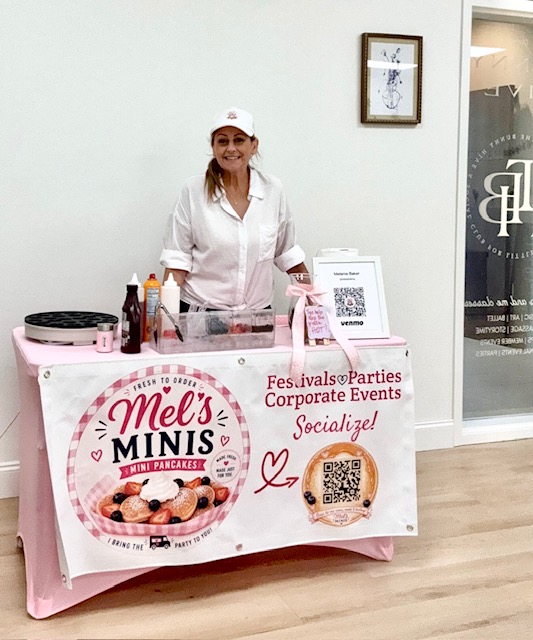 Mel serving from the Mel's Minis pink pancake cart at an event
