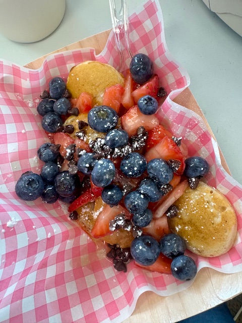 Mini pancakes loaded with strawberries, blueberries and chocolate chips in a pink gingham boat